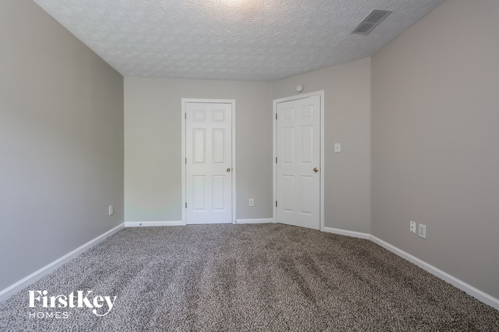 a empty room with two doors and a carpeted floor
