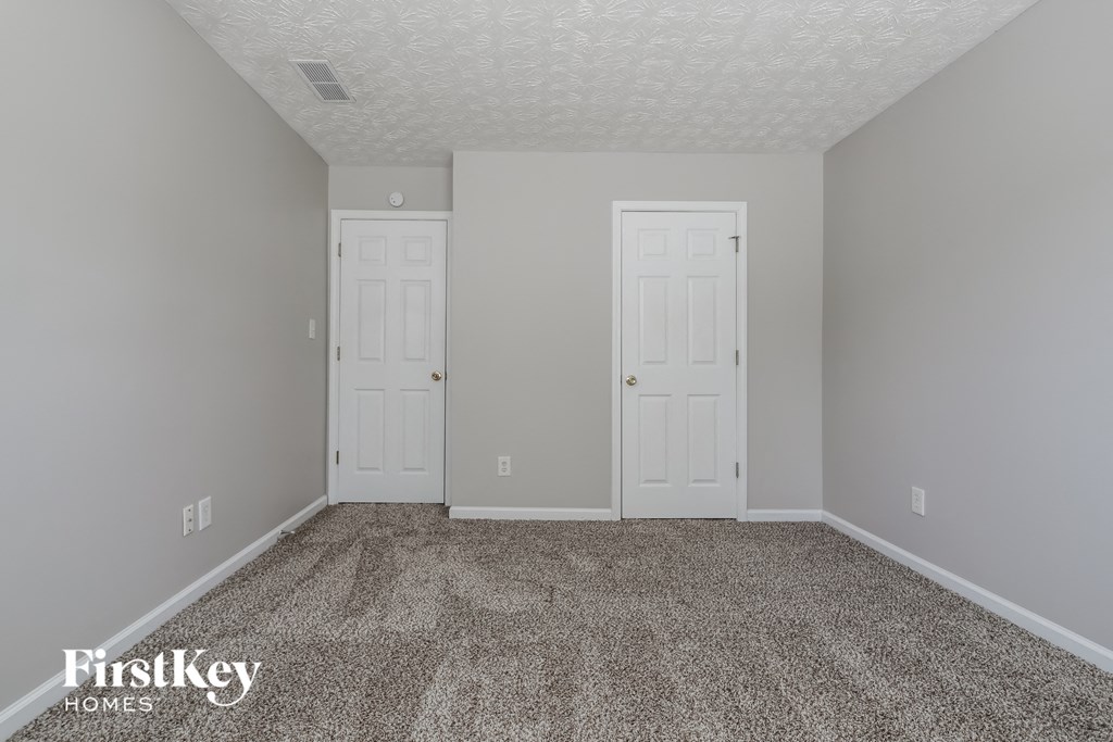 a bedroom with two doors and a carpeted floor
