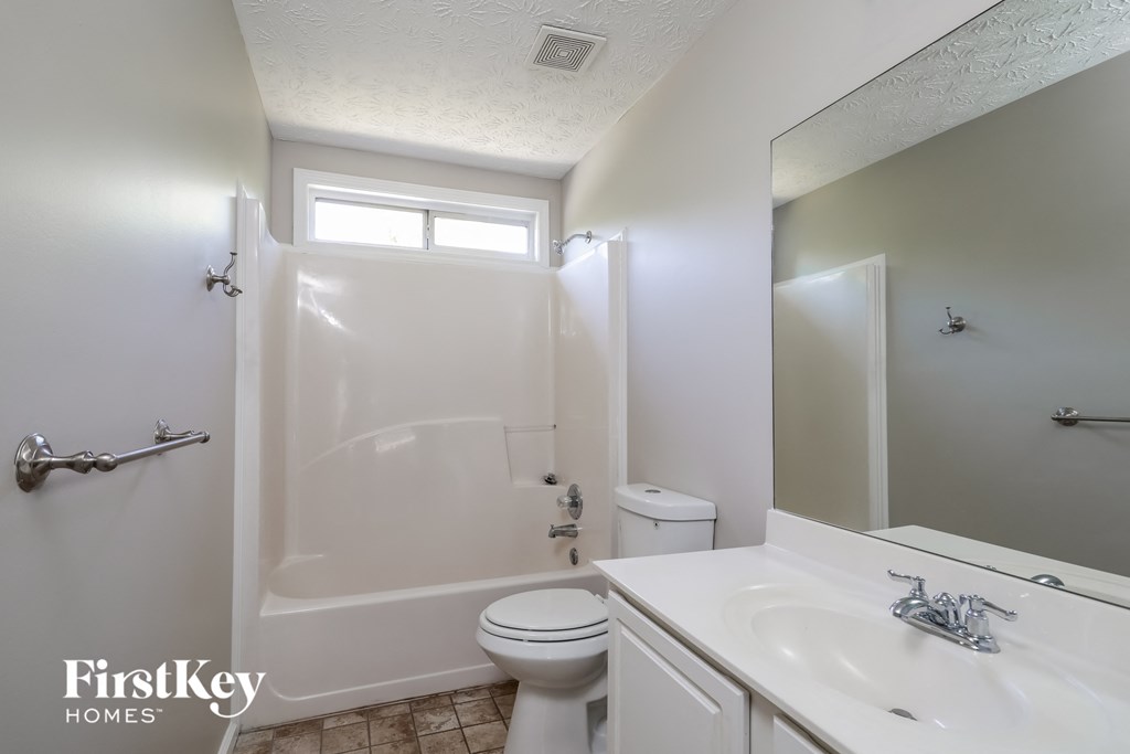 a white bathroom with a shower toilet and sink