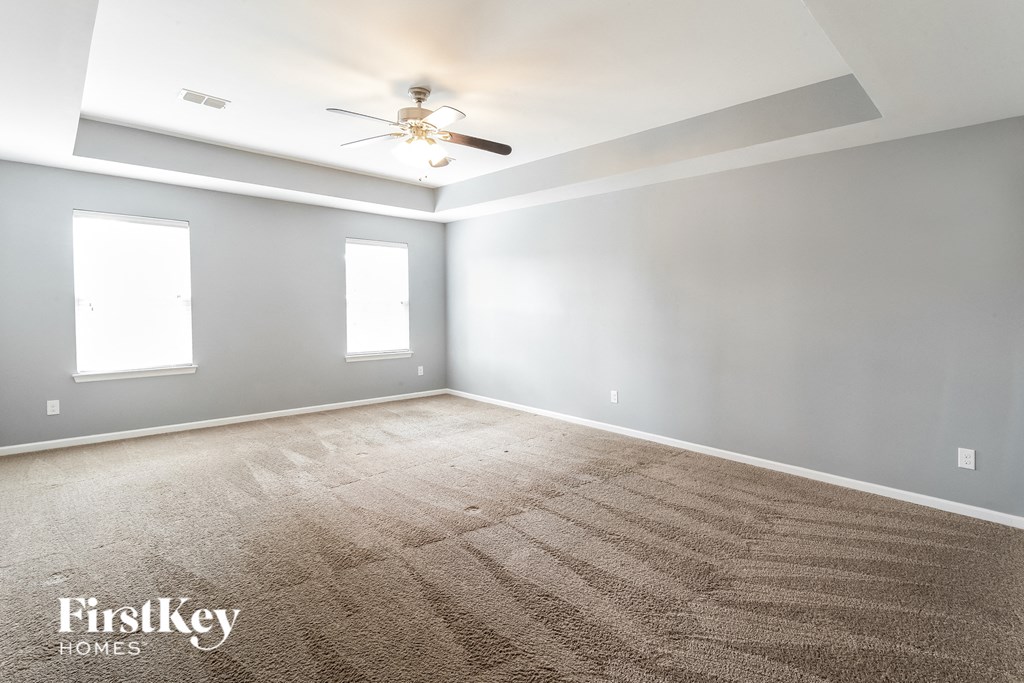 a empty room with a ceiling fan and a carpet