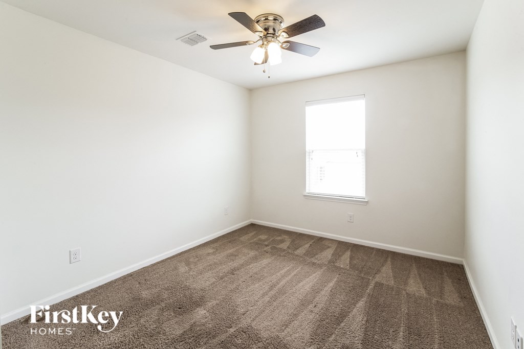 an empty room with a ceiling fan and a window