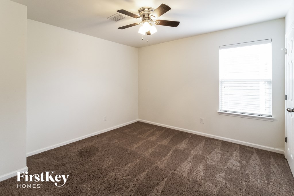 a living room with carpet and a ceiling fan