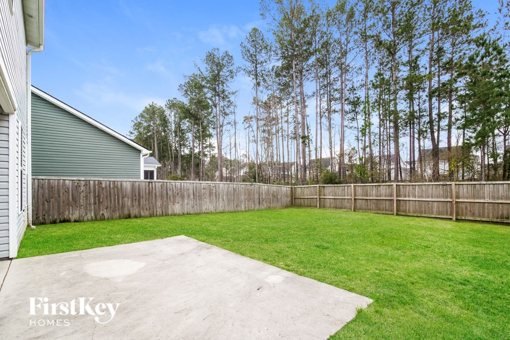 a backyard with a fence and a lawn and a house