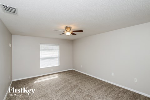 the spacious living room with ceiling fan and carpet