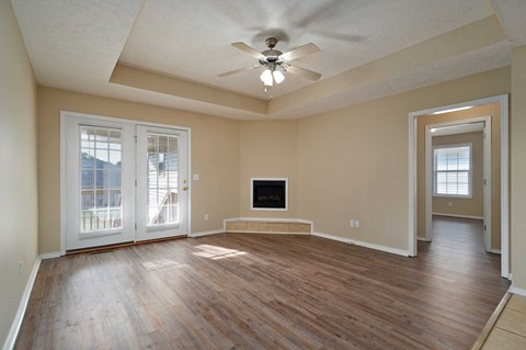 A spacious living room with a television and sliding glass doors.