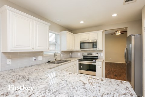 a white kitchen with stainless steel appliances and marble counter tops