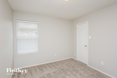 a bedroom with white walls and carpet and a white door
