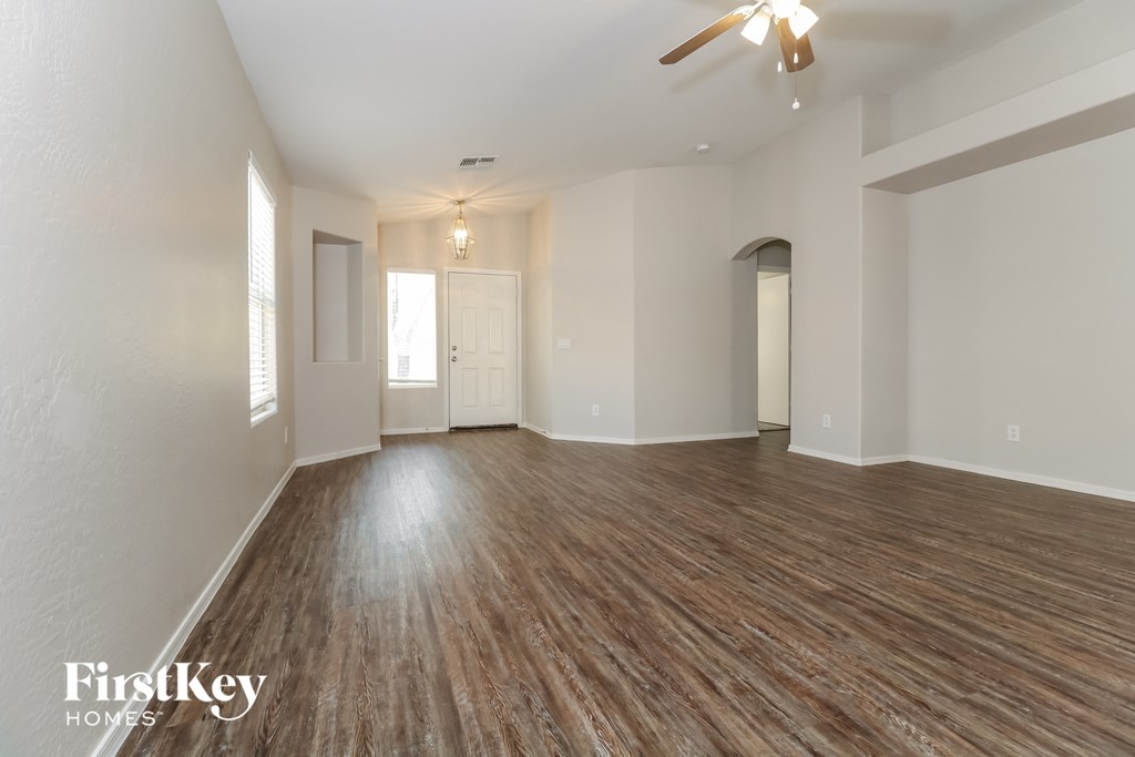 A spacious room with wooden flooring and a ceiling fan.