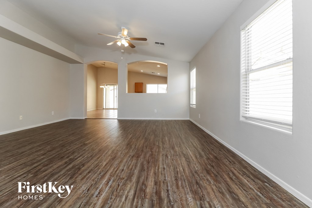 A spacious room with wooden floors and a ceiling fan.