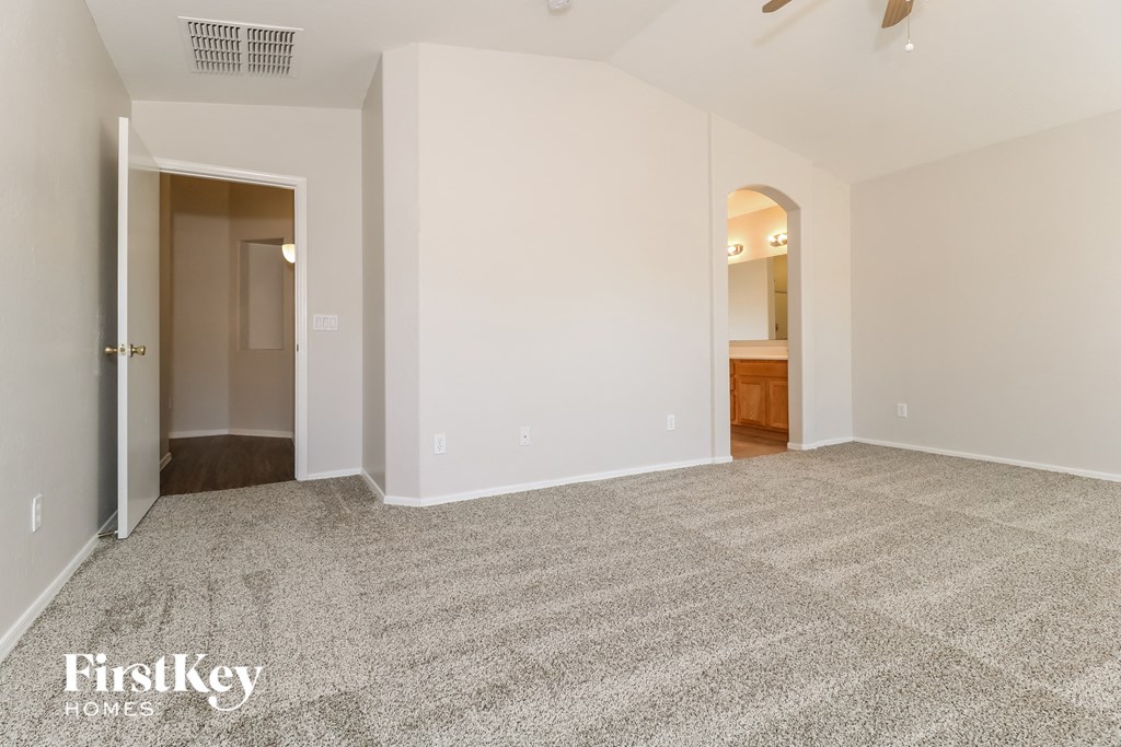 A spacious room with a carpeted floor and a doorway leading to another room.