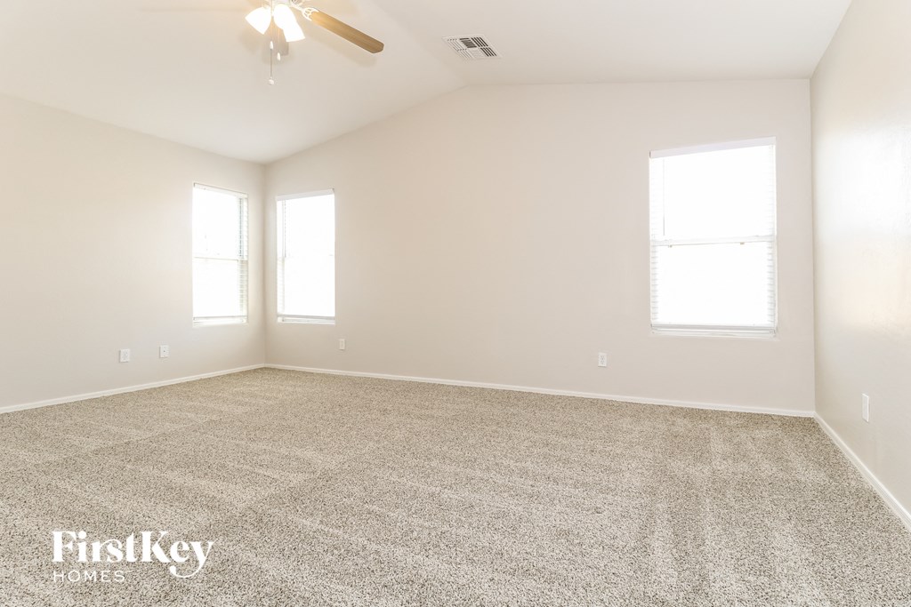 A spacious room with a carpeted floor and two windows.