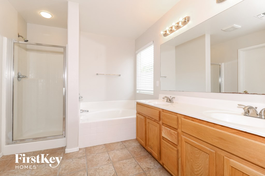 A large, well-lit bathroom with a walk-in shower and double sinks.