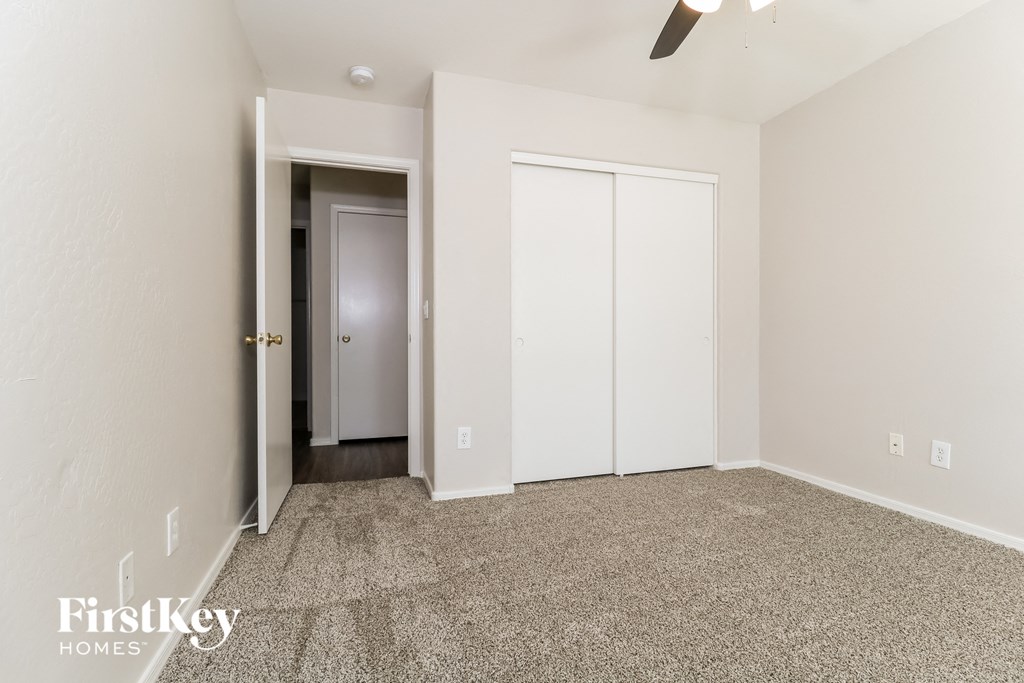 A room with a carpeted floor and a ceiling fan.