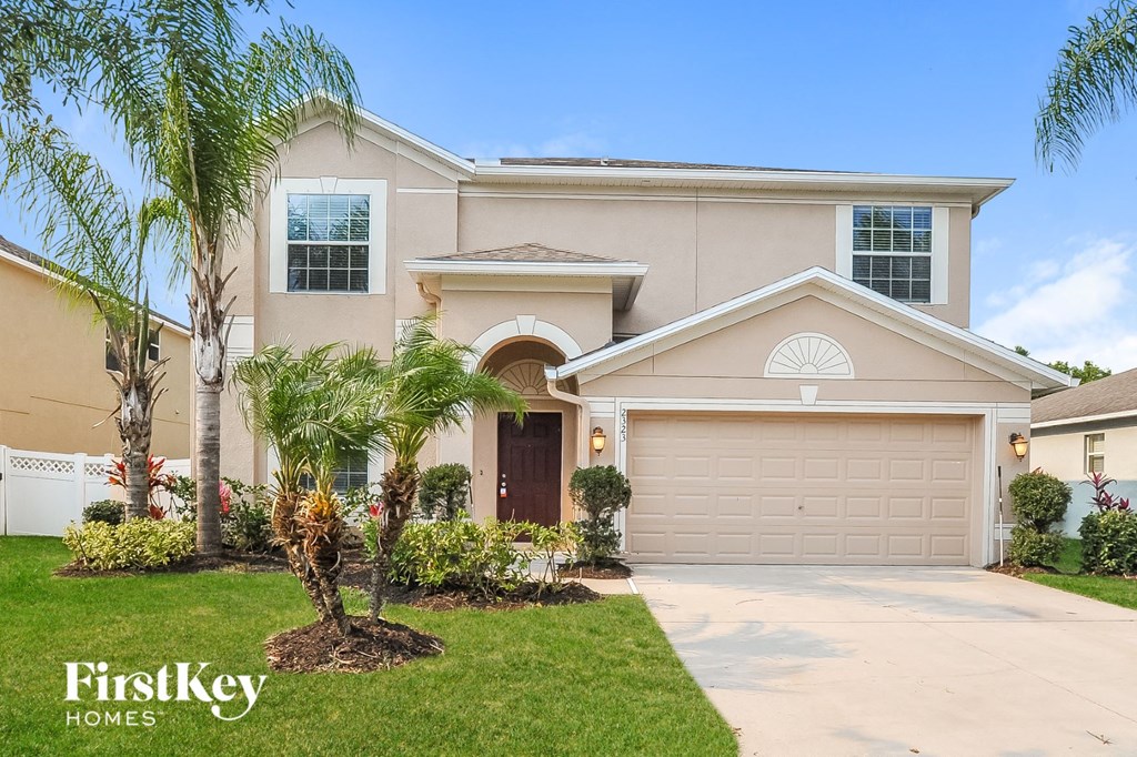 a beige house with a garage door and palm trees
