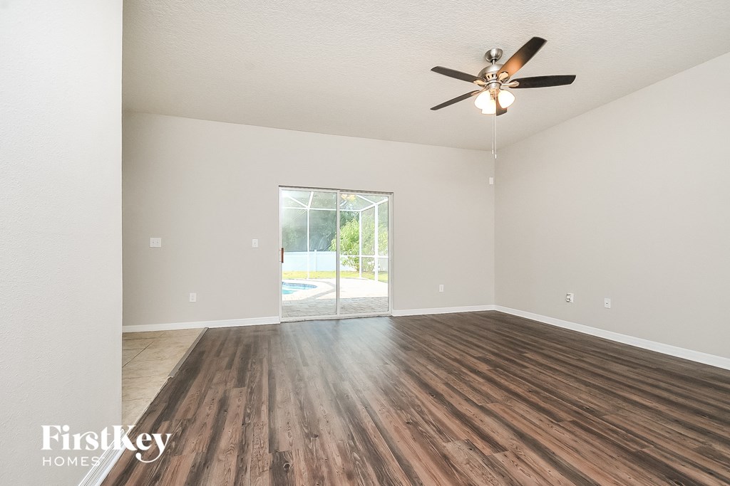 the living room of an empty house with wooden floors and a ceiling fan