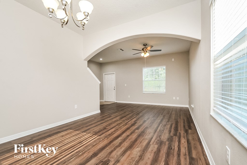 the spacious living room with wood flooring and a ceiling fan