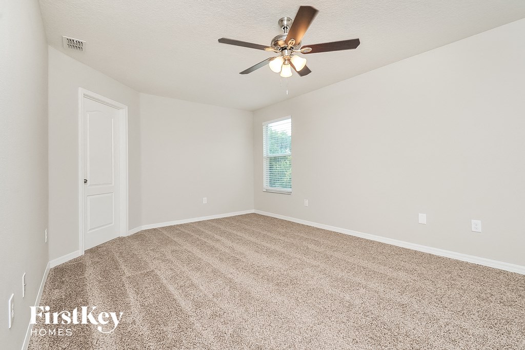 the spacious living room with ceiling fan and carpet