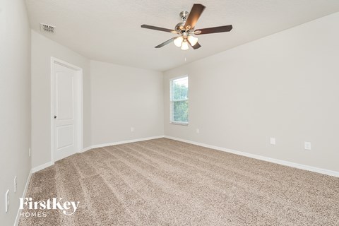 the spacious living room with ceiling fan and carpet