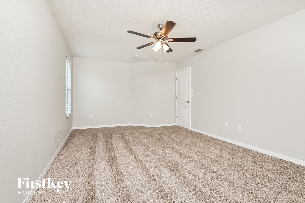 a spacious living room with carpet and a ceiling fan