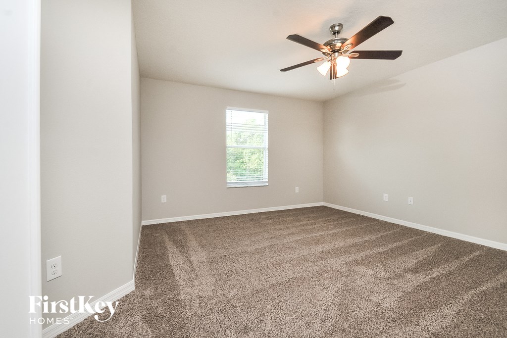 the spacious living room with carpet and ceiling fan