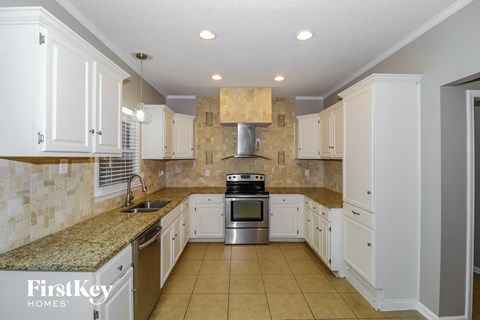 a kitchen with white cabinets and granite counter tops and a sink