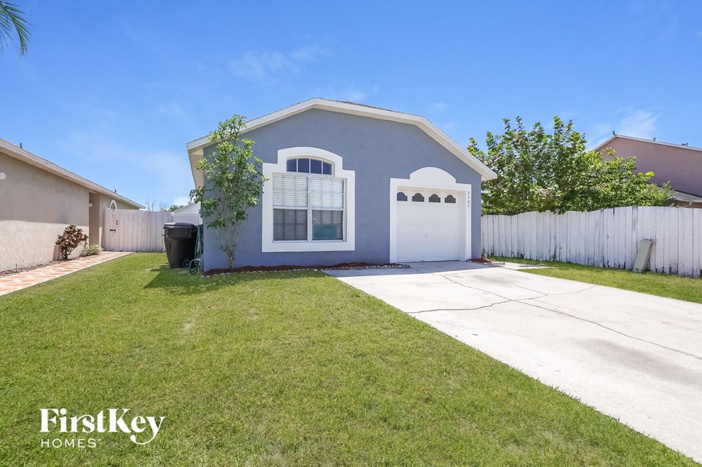 a blue house with a driveway and a white fence