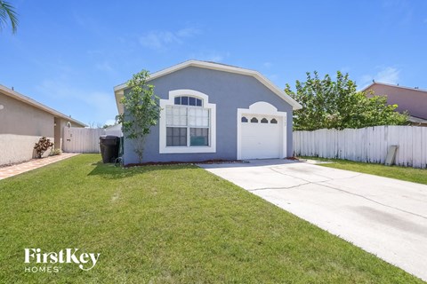 a blue house with a driveway and a white fence