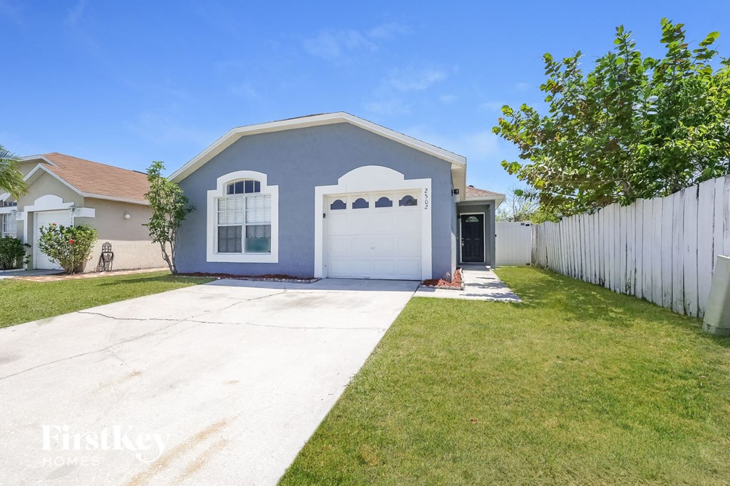 a blue house with a white fence and a driveway