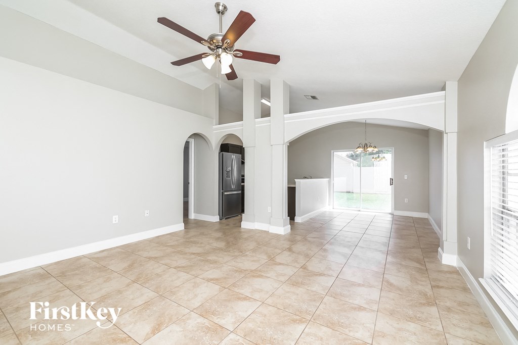 an empty living room with a ceiling fan and tile flooring