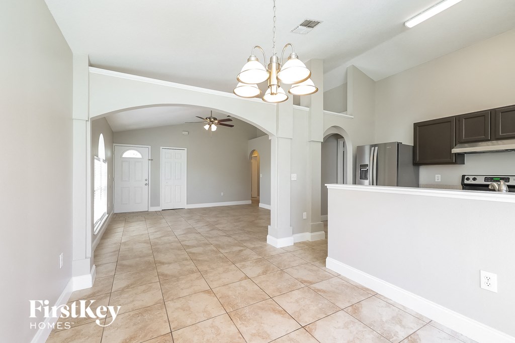 an empty kitchen and living room with a white counter top and a ceiling fan