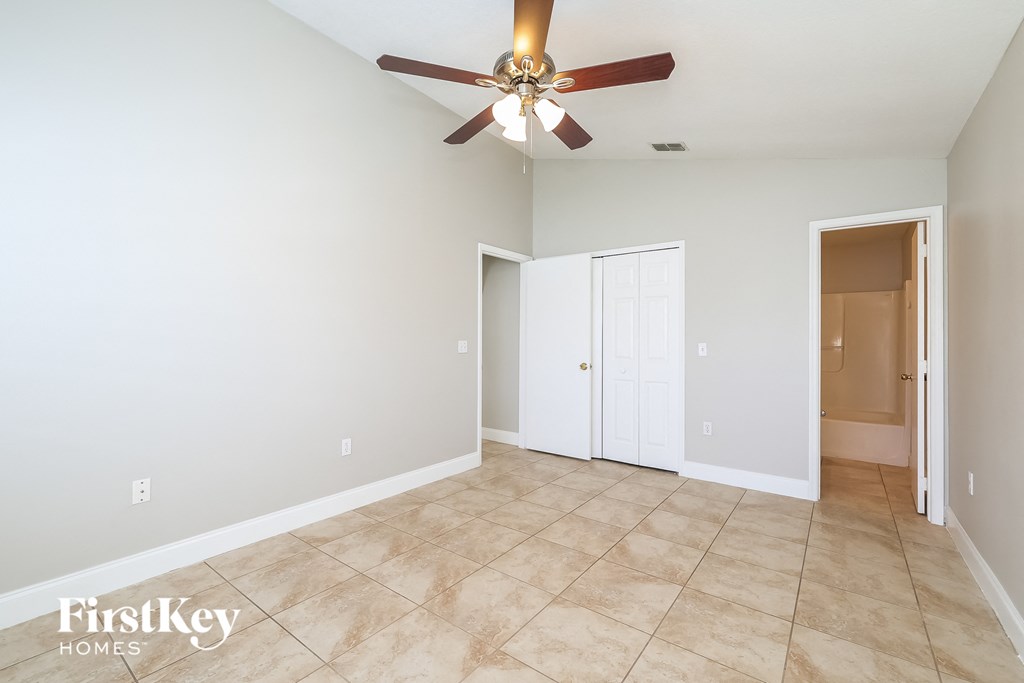 a empty living room with a ceiling fan and a door to a closet