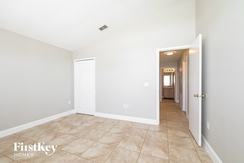 the living room and hallway of a home with white walls and tile flooring