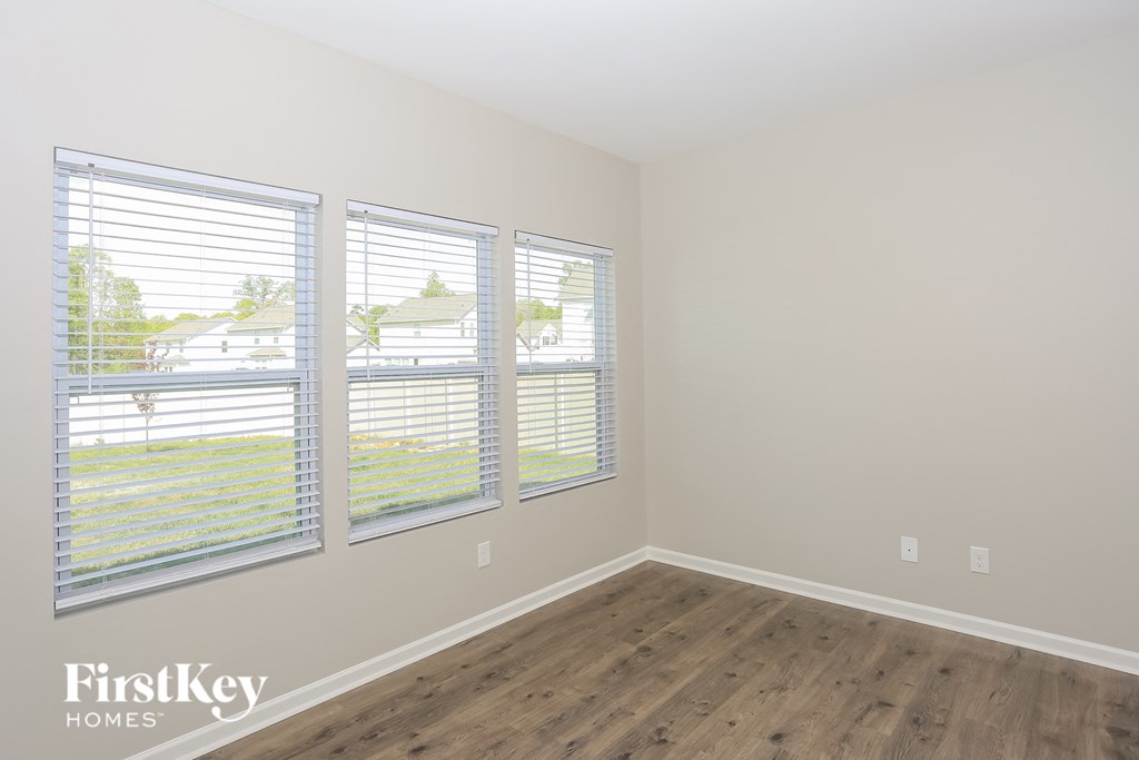 A room with wooden floors and three windows.