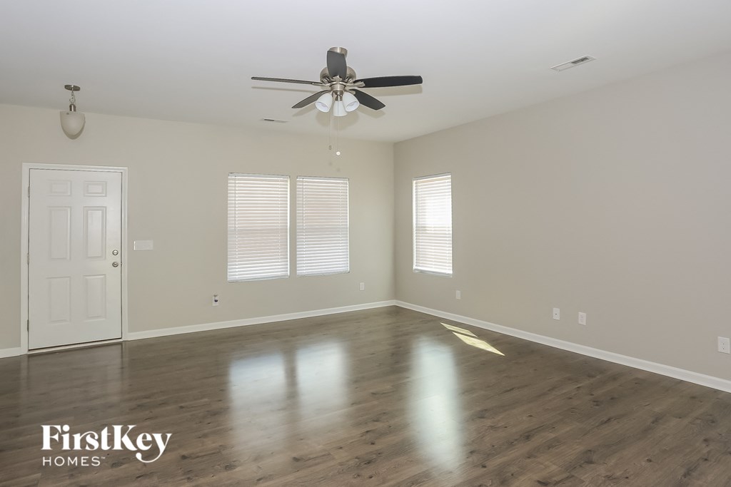 A spacious room with a ceiling fan and wooden flooring.