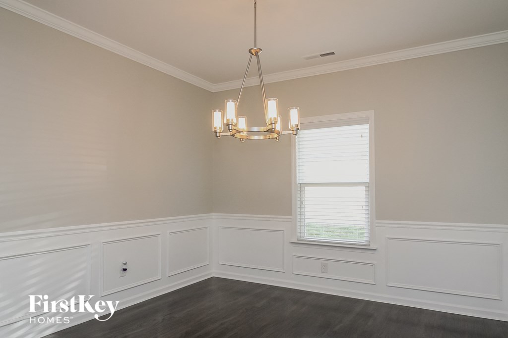 a dining room with white wainscoting and a chandelier
