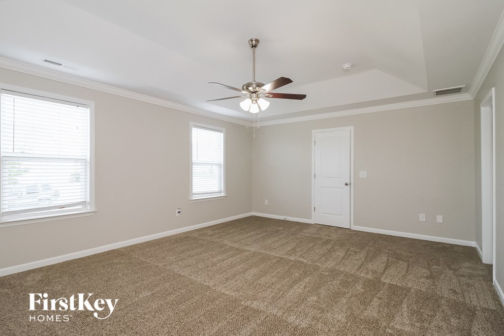 an empty living room with a ceiling fan and a door