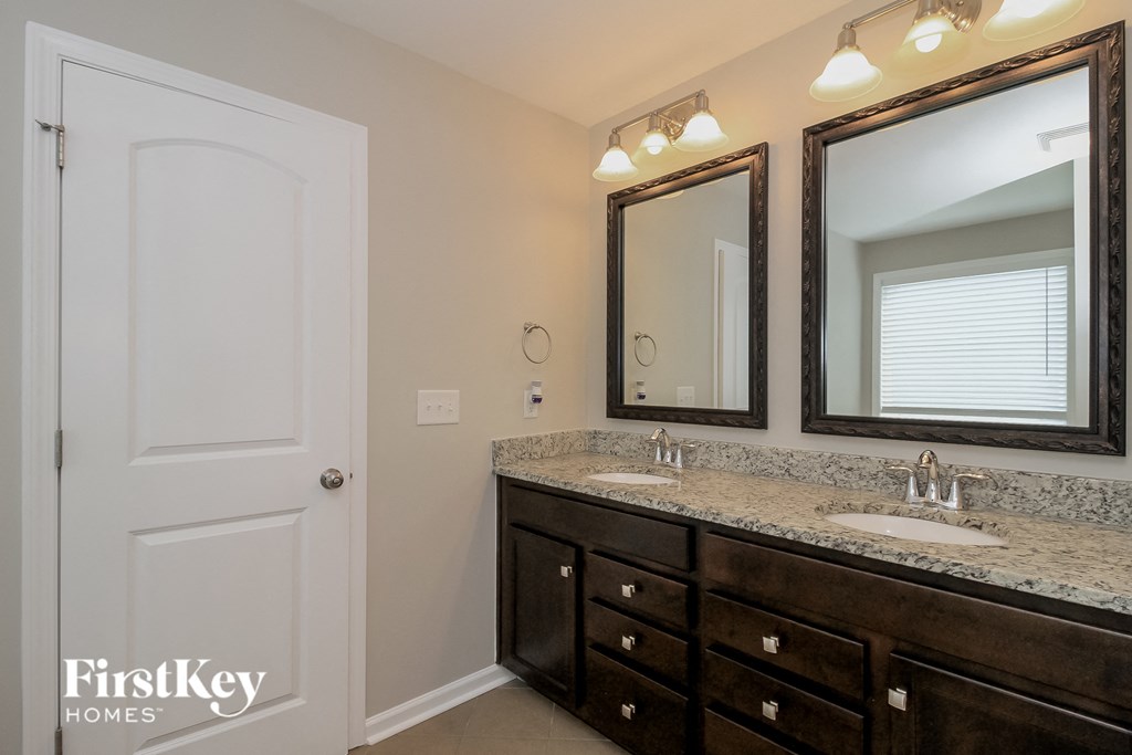 the master bathroom has a large vanity with two sinks and two mirrors