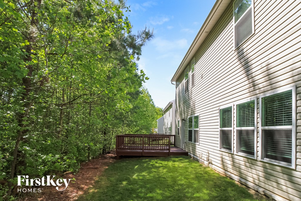 the back of the house with a deck and a wood deck