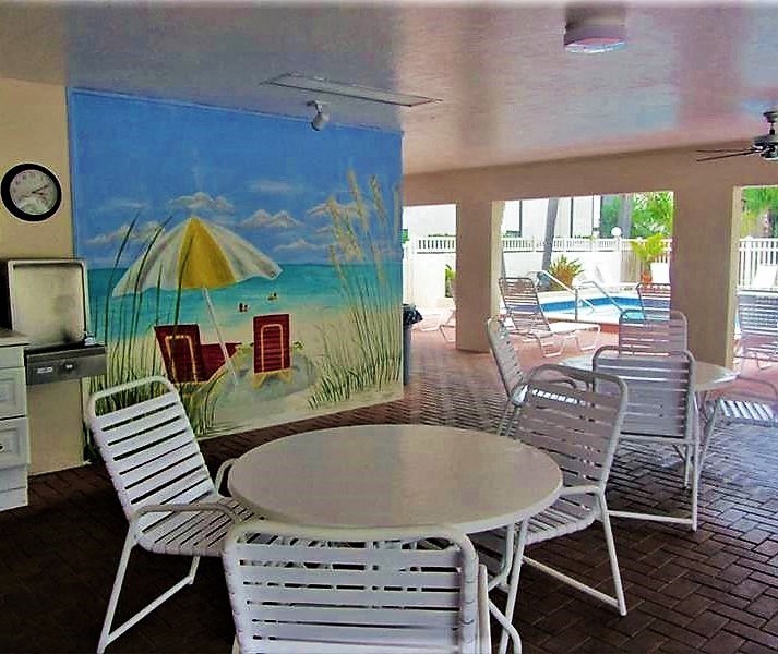 a patio with tables and chairs and a painting on the wall