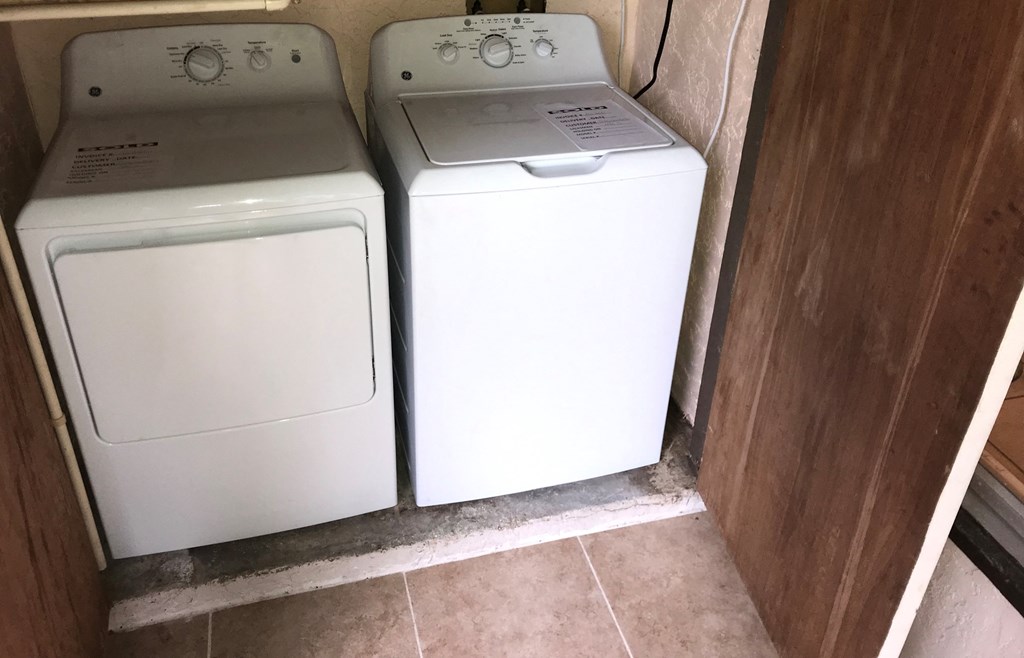 two washers and a dryer in the corner of a room