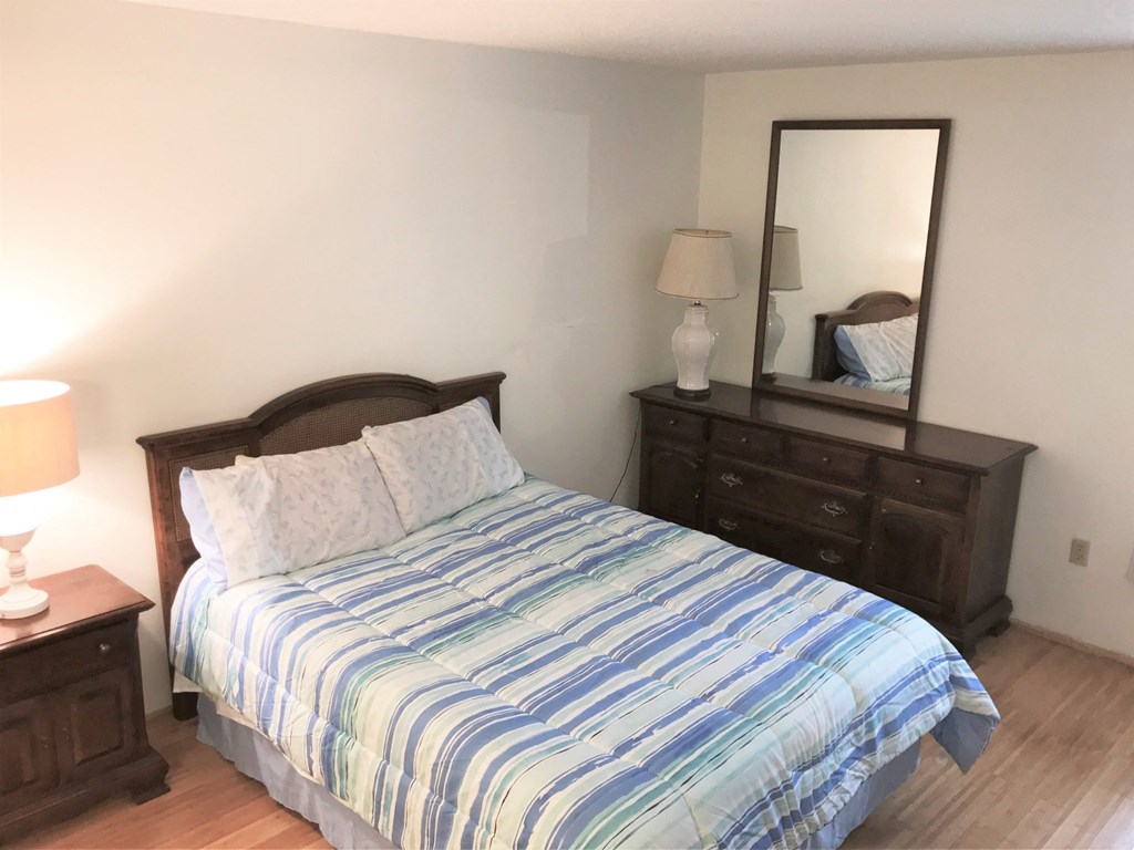 a bedroom with a bed and a dresser and a mirror