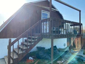 the back of the house with stairs and a wooden deck