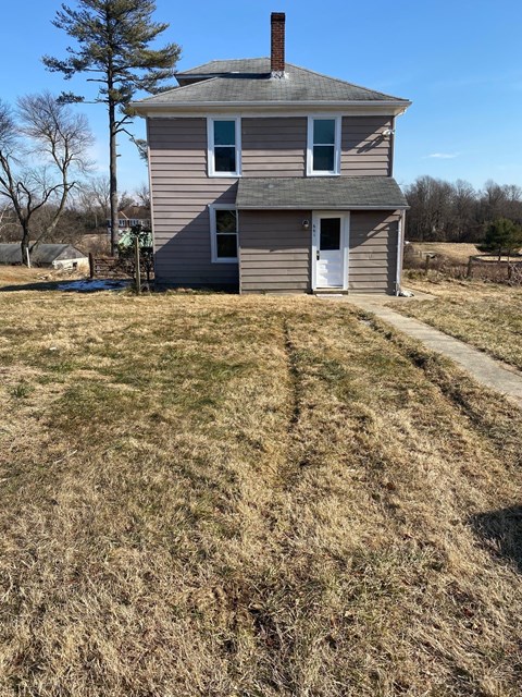 an old house with a dirt road in front of it