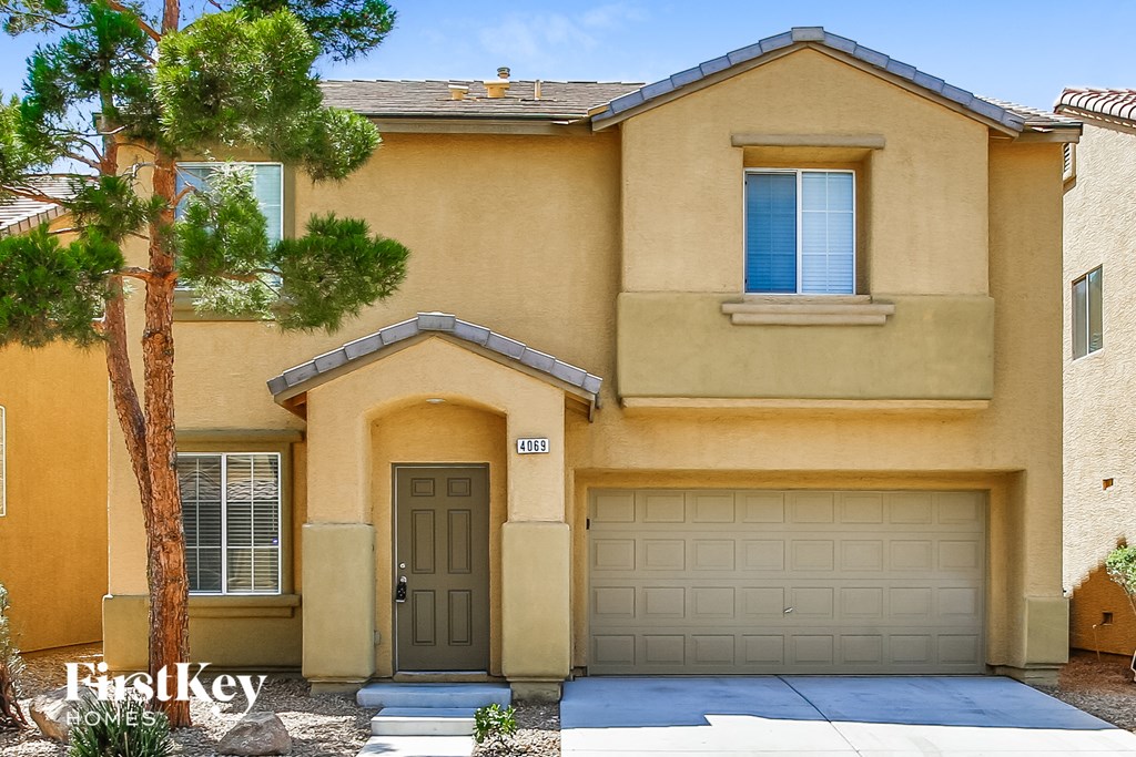 a beige house with a garage door and a tree