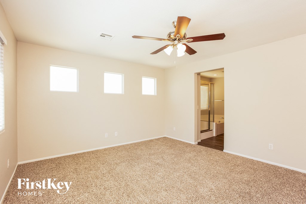 a empty living room with a ceiling fan and a carpet