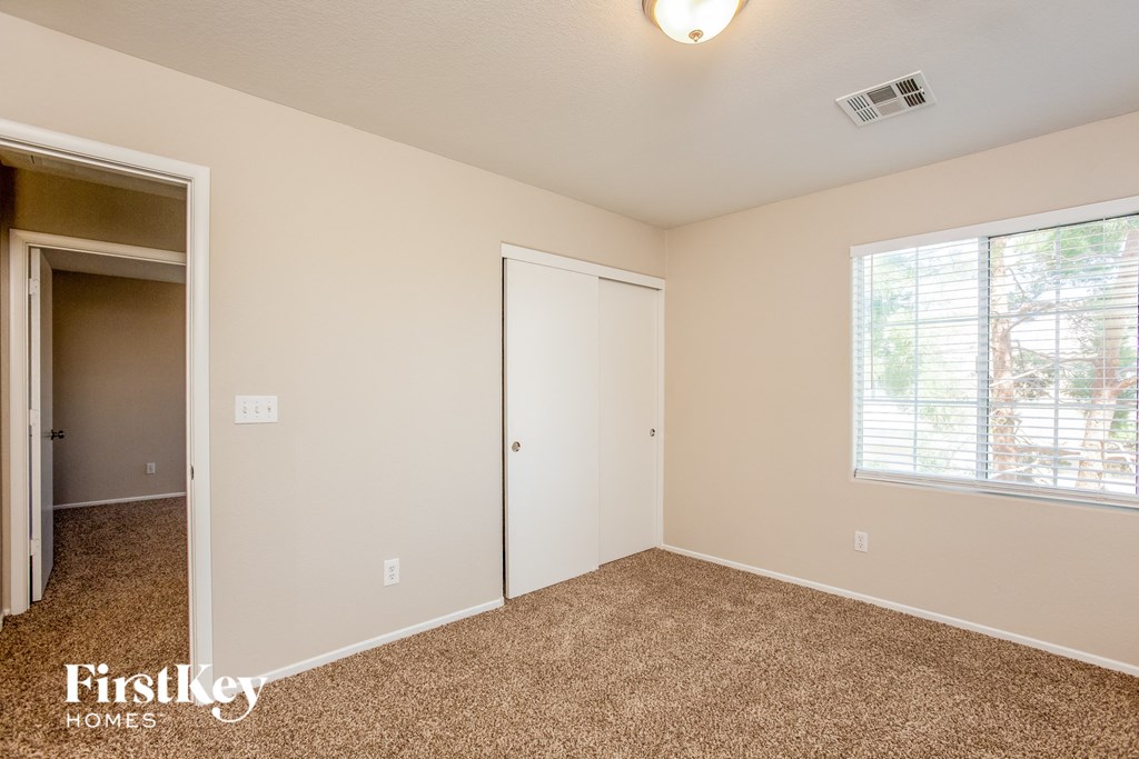 a bedroom with carpet and a door to a closet and a window