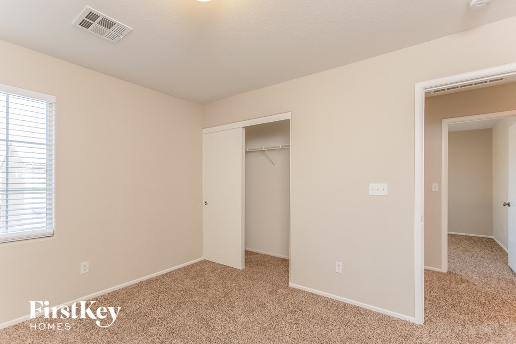 a bedroom with a closet and a window and a carpeted floor