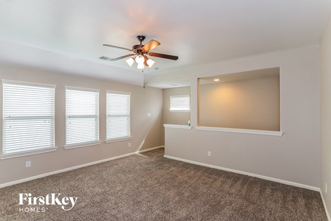 A spacious room with a ceiling fan and carpeted floor.