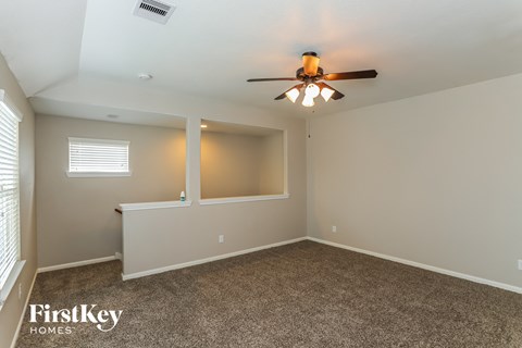 A room with a ceiling fan and a window with blinds.