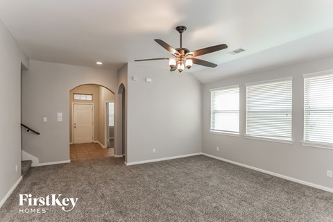 A spacious room with a ceiling fan and carpeted floor.
